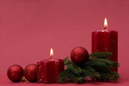 Christmas arrangement of candles and baubles, on red backgroundの写真素材
