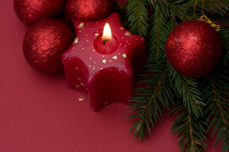 Christmas arrangement of candles and baubles, on red backgroundの写真素材