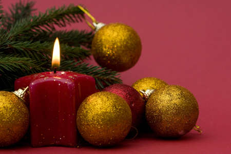 Christmas arrangement of candles and baubles, on red backgroundの写真素材