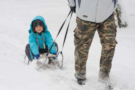 kid sledging while it is snowing and cold