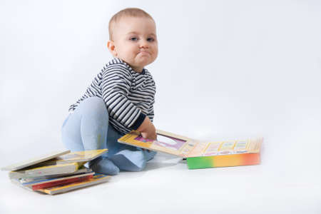 baby boy playing with books, on whiteの写真素材
