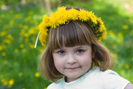little, cute girl wearing yellow garland on a summer dayの写真素材