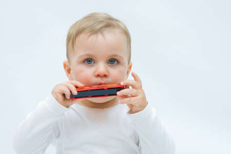 little, cute boy playing harmonica, on white