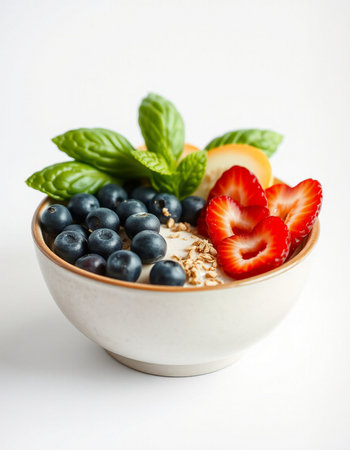 Healthy breakfast bowl with oatmeal, berries and mint on white background