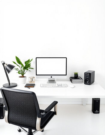 Workplace with computer, books, plant and speakers on a white table