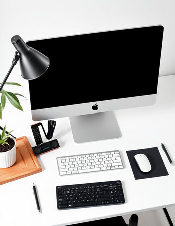 Workplace with computer, keyboard, mouse, lamp and plant.