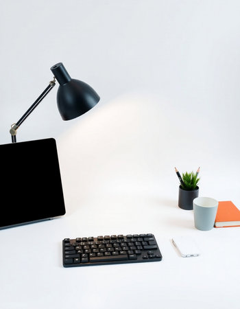 Office desk with laptop, coffee cup and black lamp on white backgroundの写真素材