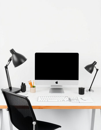 Workplace with computer on table, lamp and coffee cup on white wall backgroundの写真素材