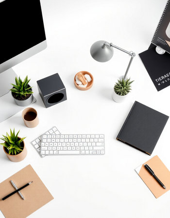 Top view of modern workplace with computer, stationery and plants on white backgroundの写真素材