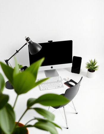 Office desk with computer, supplies and plant on the white wall backgroundの写真素材