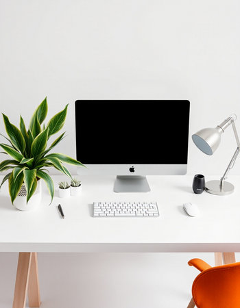 Modern workplace with computer, keyboard, lamp and plant on white tableの写真素材
