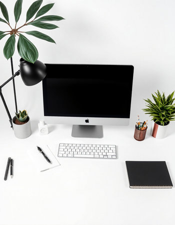 Top view of modern workspace with computer, stationery and green plants on white backgroundの写真素材