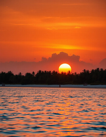 Beautiful sunset on the beach with the sun setting behind the cloudsの写真素材