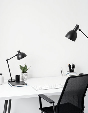 workplace with black chair, lamp and computer on white wall backgroundの写真素材