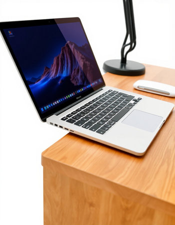 Laptop on a wooden table with a lamp and a mouse on a white backgroundの写真素材