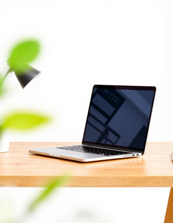 Laptop on a wooden table with a white wall in the backgroundの写真素材