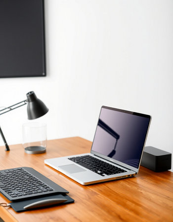Laptop on a desk in a room with a white wall.