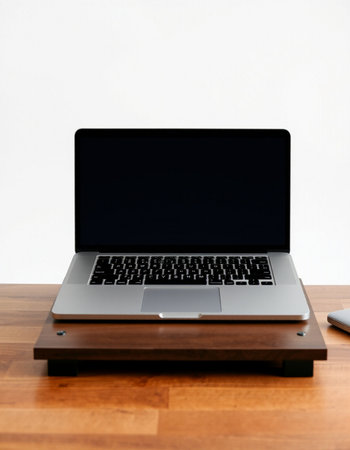 Laptop on a wooden desk with white wall in the background.