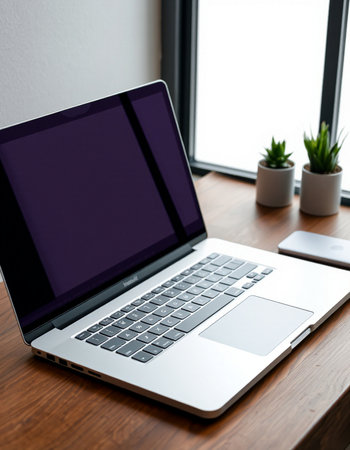 Laptop with blank screen on wooden table near window at home office