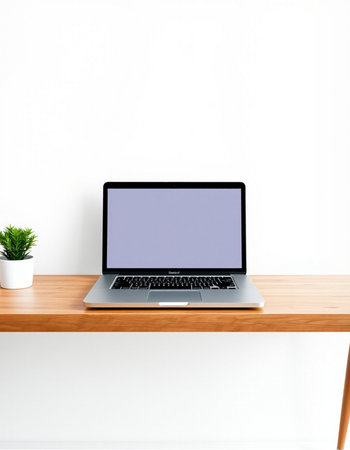 Laptop with blank screen on wooden table and white wall background.