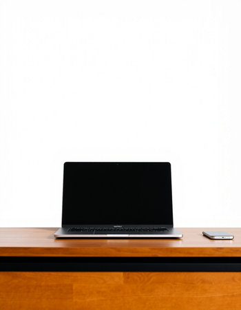 Laptop on a wooden desk with a white wall in the background