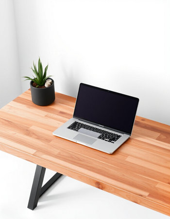 Laptop with blank screen on wooden table on white wall background.