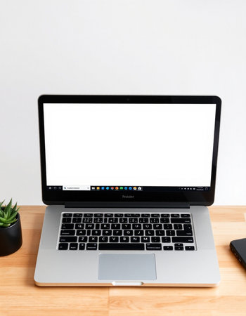 Laptop with blank screen on wooden desk and white wall background.の写真素材