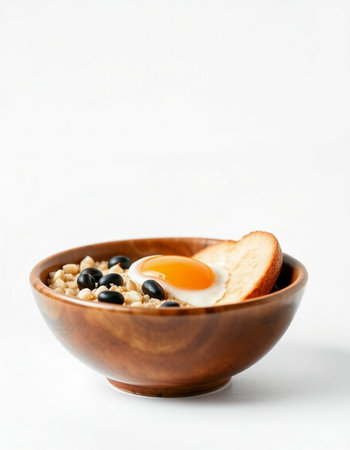 Oatmeal porridge with egg in a wooden bowl on a white backgroundの写真素材