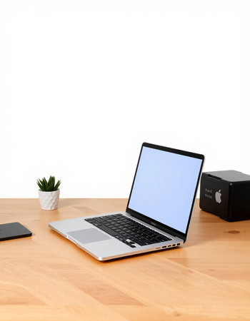 Laptop with blank screen on wooden table and white wall background.