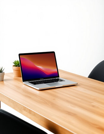 Laptop on a wooden table with a white wall in the background