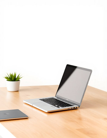 Laptop and smartphone on the wooden table with white wall background.