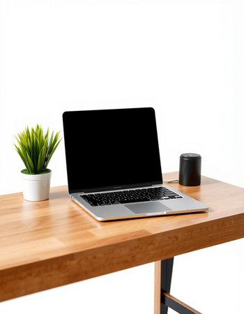Laptop with blank screen on wooden table with white wall background.