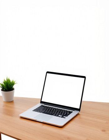 Laptop with blank screen on wooden table and white wall background.