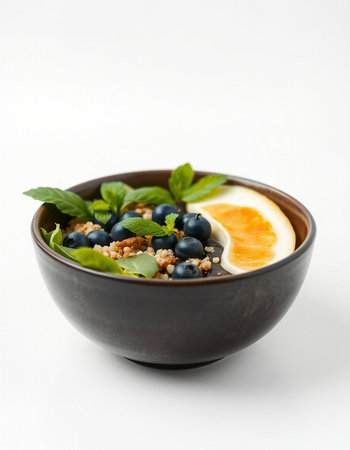 Bowl of quinoa porridge with blueberries and mint on white backgroundの写真素材
