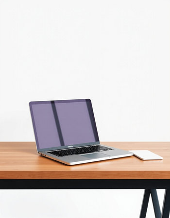 Laptop on a wooden table with a white wall in the background