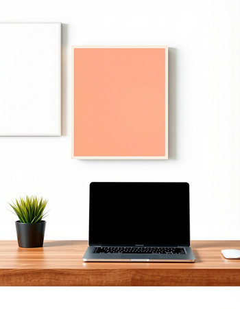 Laptop with blank screen on wooden table and white wall background.