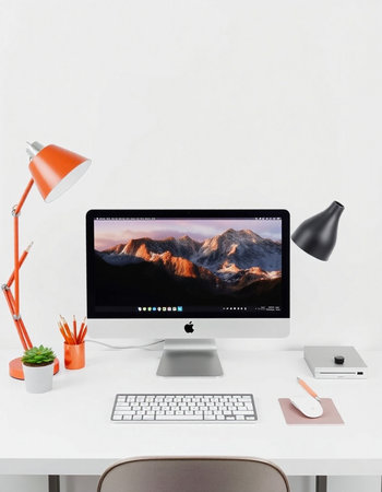 Modern designer desktop with computer, lamp and other items.