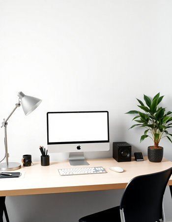 Modern workplace with blank computer screen, coffee cup, stationery and plant in front of white wallの写真素材