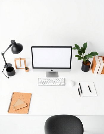 Workplace with blank computer screen, stationery and plant on table