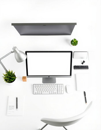 Top view of modern workplace with blank screen computer monitor, stationery and other items on white backgroundの写真素材