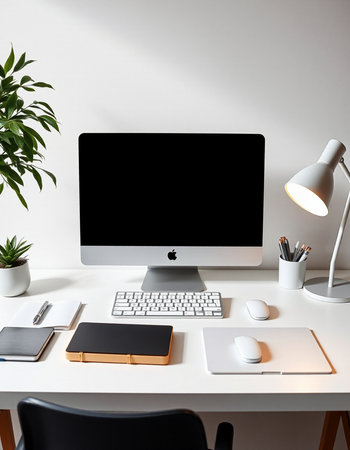 workplace with computer, stationery and plant on table in officeの写真素材