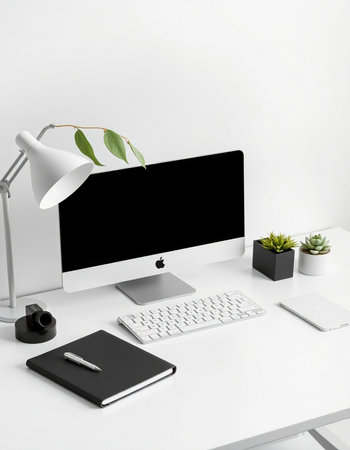 workplace with computer, stationery and plant on white wall background