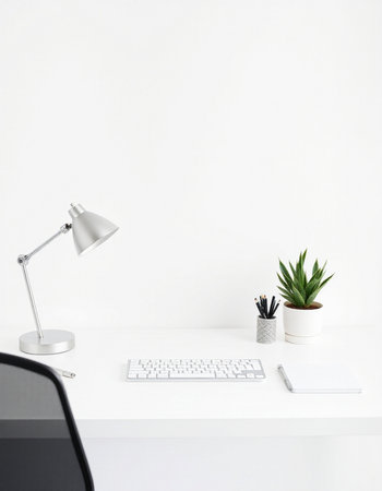 Office desk with computer and plant on white wall background.の写真素材