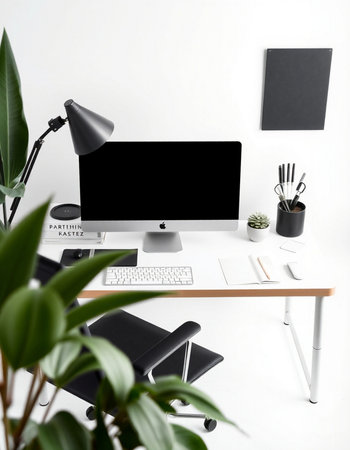 Modern workplace with computer, stationery and plant on white wall backgroundの写真素材