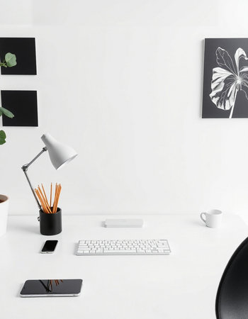 Minimalistic workspace with computer, keyboard, coffee cup, mobile phone, stationery and decorations on white wallの写真素材