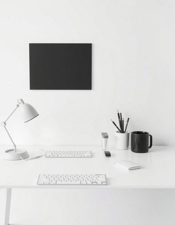 White desk with computer, keyboard, mouse, coffee cup and blank black poster on the wall