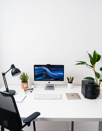 workplace with computer, lamp and plant on white wall background.