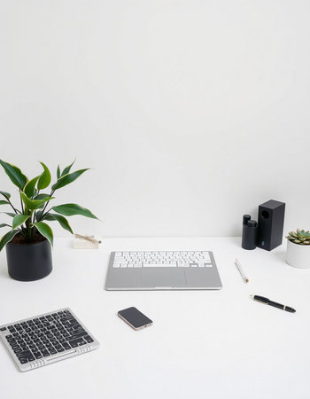 Minimal workspace with laptop, smartphone, stationery and plant on white background