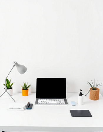 Workplace with laptop, coffee cup, mobile phone and plant on white desk