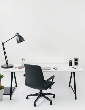 workplace with black armchair, computer, lamp and plant on white tableの写真素材